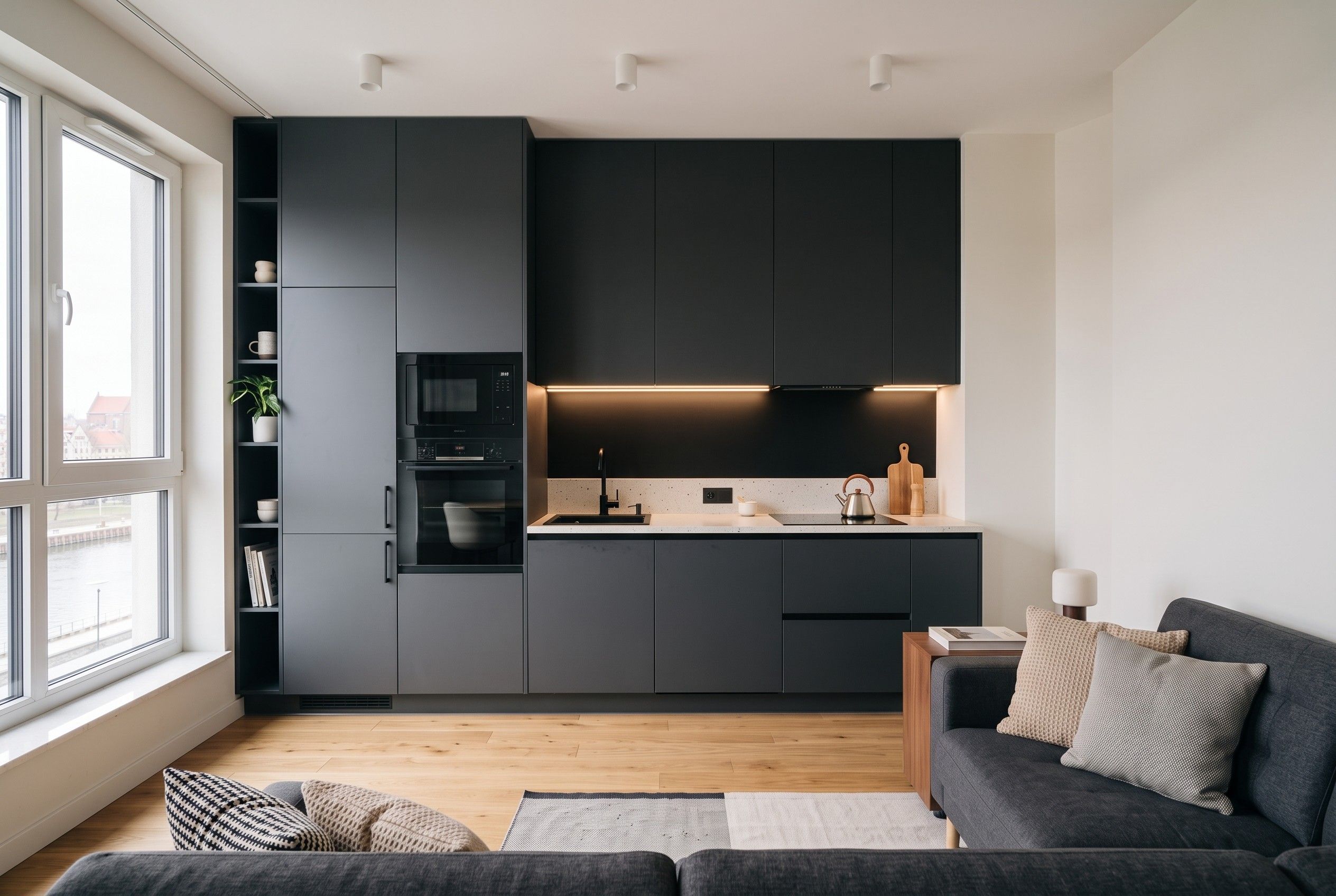 Aneks kuchenny otwarty na salon w apartamencie, widok od strony kanapy